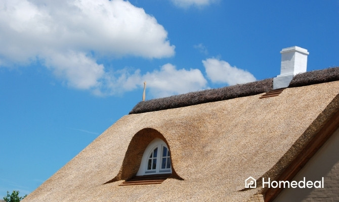 Woning met een traditioneel rieten dak, een dakkapel en een schoorsteen. Het rieten dak geeft de woning een karakteristieke uitstraling en biedt goede isolerende eigenschappen.
