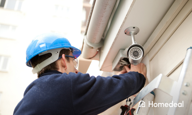 Vakspecialist monteert een beveiligingssysteem met camera's onder de dakrand buiten