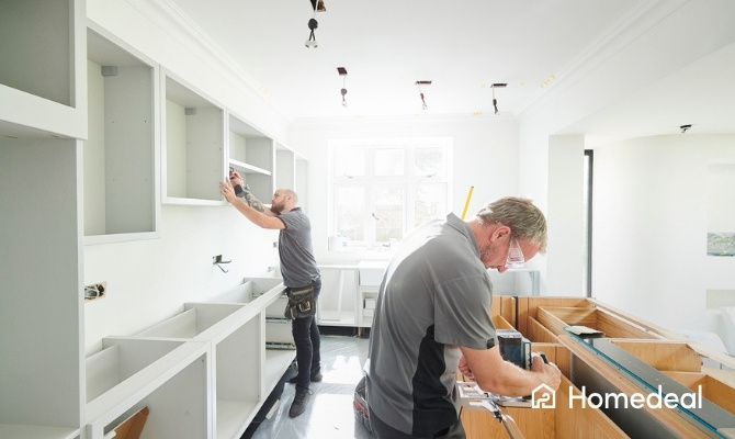 Twee vakspecialisten voeren in een keukenrenovatie uit in een witte keuken.