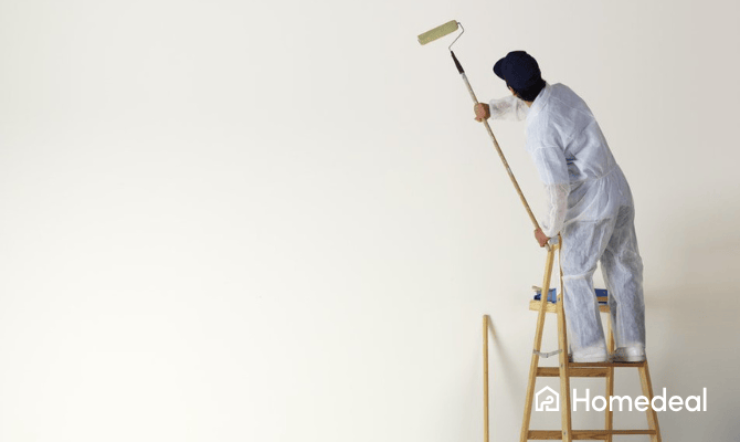 Schilder op een trap die de muur egaal verft met een roller op een stok