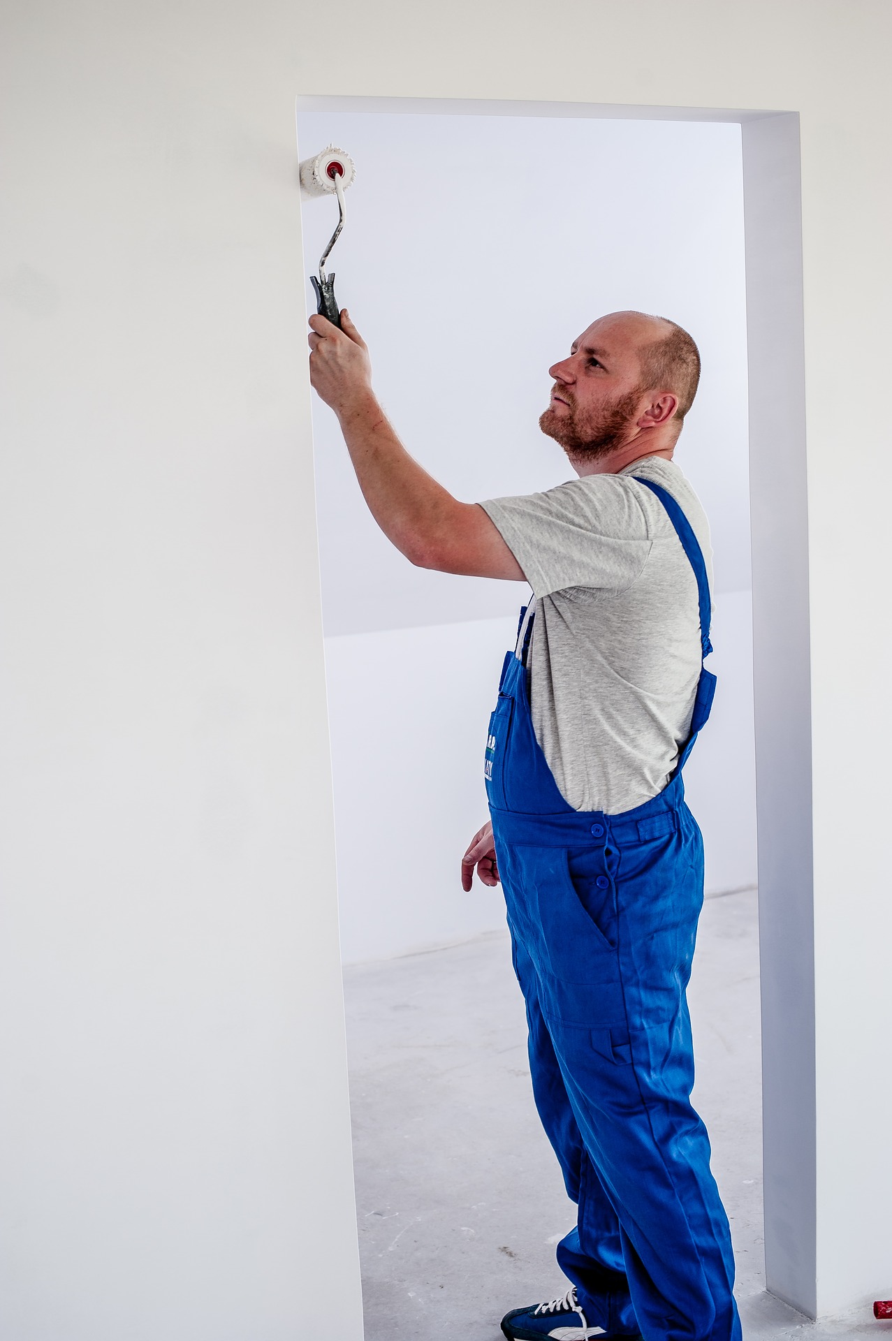 schilder in blauwe overal die aan het verven is