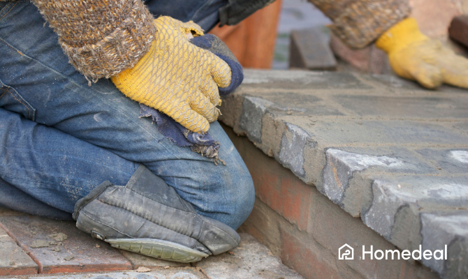 Man met kniebeschermers en handschoenen is bezig met bestraten