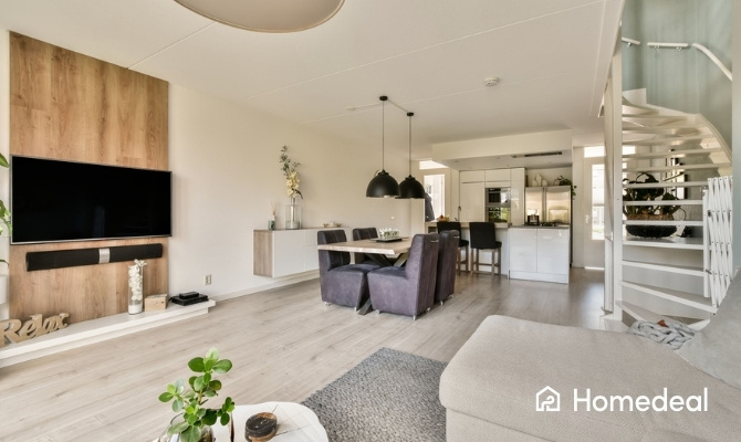 Open woonkamer met lichte vloer, open keuken en een open trap die leidt naar de bovenverdieping.