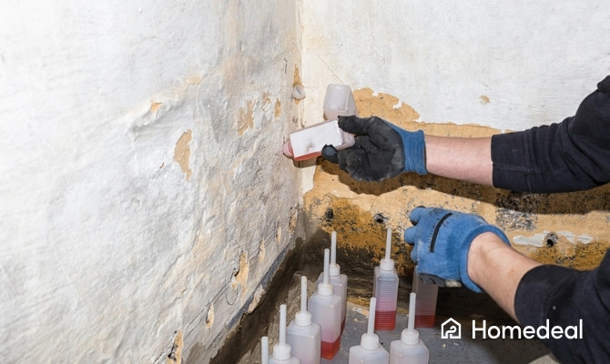 Behandeling van optrekkend vocht door muurinjectie, waarbij injectievloeistof in de onderzijde van een beschadigde muur wordt aangebracht.