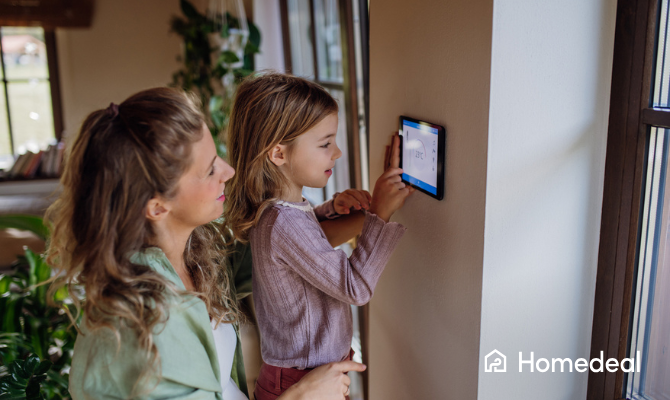 Meisje helpt haar moeder met het aanpassen van de temperatuur op een slimme thermostaat aan de muur