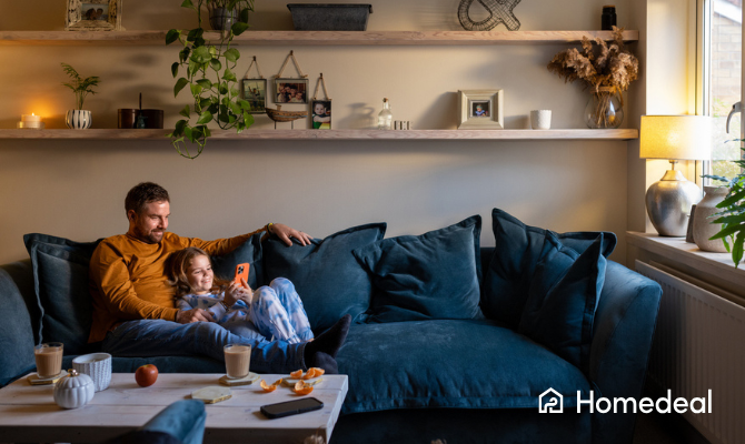 Vader zit relaxed met dochter op de bank in comfortabel geïsoleerd huis