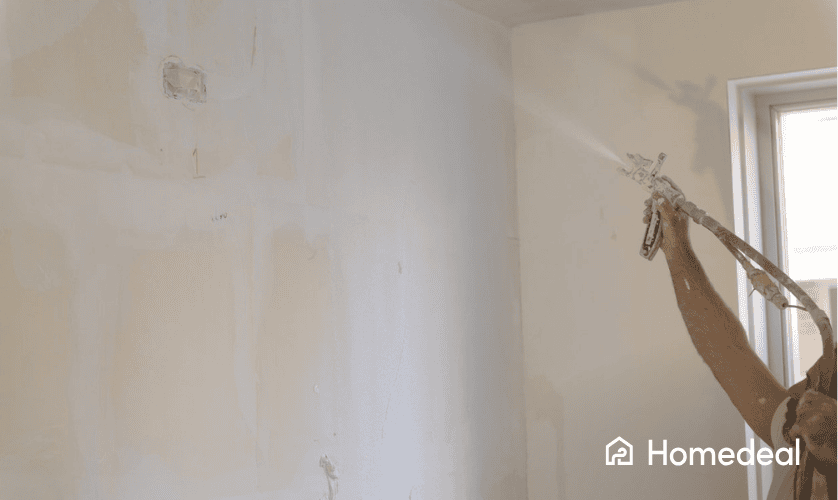 Verfspuit die de muur wit spuit in handen van een schilder