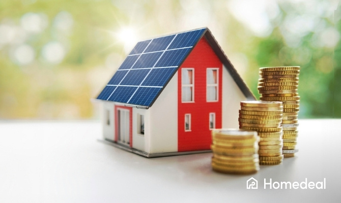 Modelhuis met zonnepanelen op het dak en stapels munten ernaast, symbool voor besparing en opbrengst van zonnepanelen.