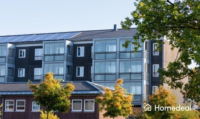 Modern appartementencomplex met op het dak gehuurde zonnepanelen, een duurzame oplossing voor bewoners van appartementen om gezamenlijk zonne-energie op te wekken.
