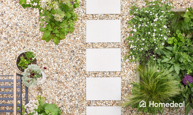 Bovenaanzicht van een tuin met grind en een looppad met tegels daar doorheen