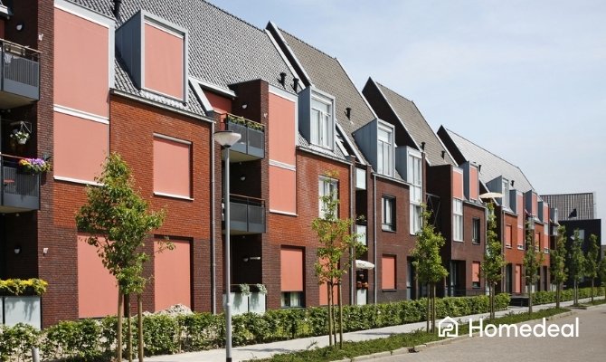 
Rij moderne Nederlandse woningen met rode bakstenen gevels en opvallende terracotta-kleurige screens als beste zonwering.