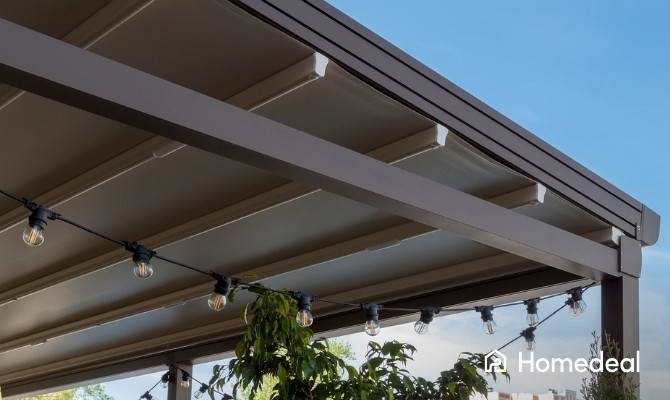 Moderne zonnescherm overkapping met geïntegreerd doek en sfeerverlichting boven een terras onder een blauwe lucht.