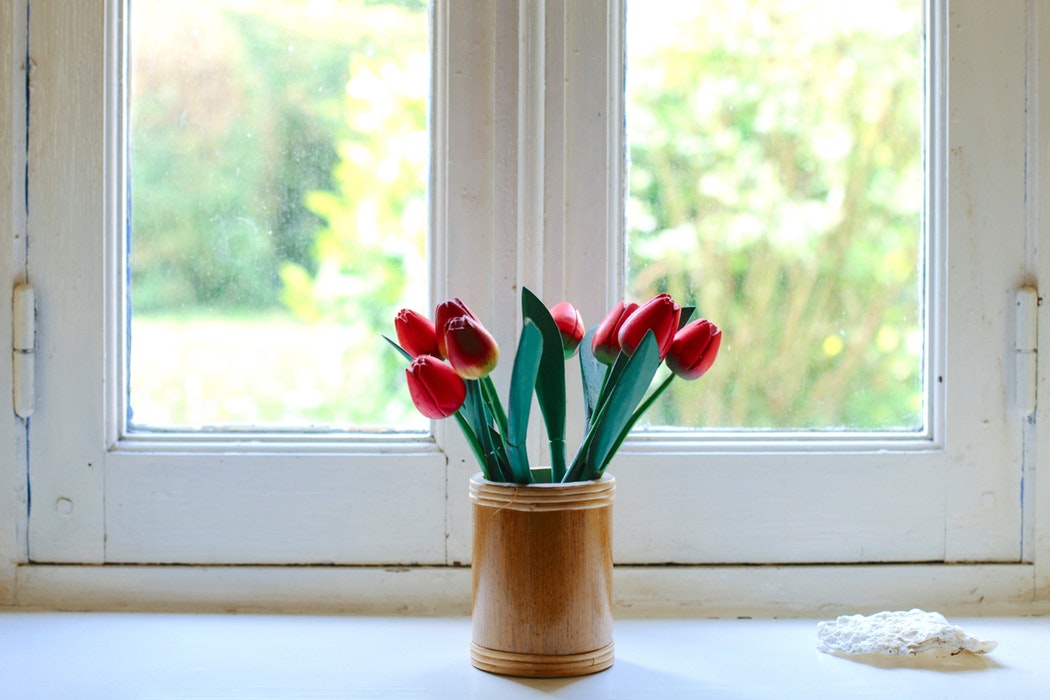 Vaas met houten tulpen voor een raam