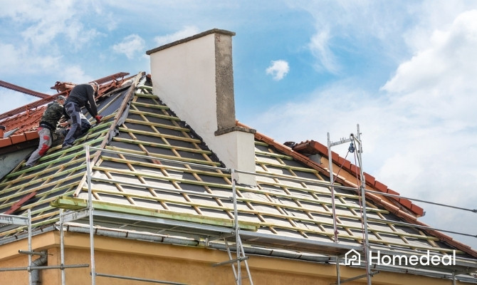 Dakbeschot vervangen tijdens een dakrenovatie waarbij dakdekkers de dakpannen hebben verwijderd en werken aan de onderconstructie van een schuin dak.