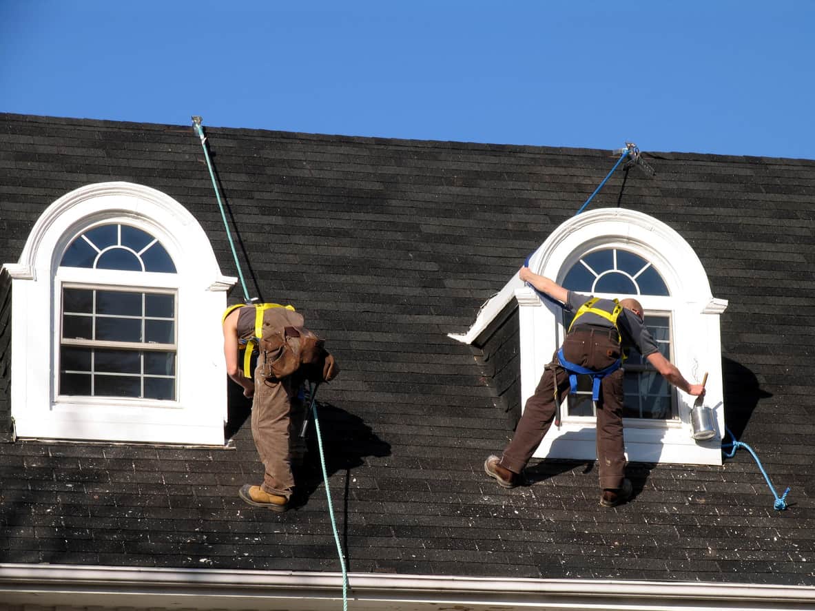 2 schilders vast aan een touw die dakkapellen verven