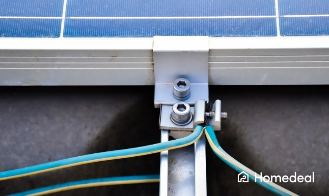 Close-up van de aardaansluiting van een zonnepaneel, waarbij geel-groene kabels zijn bevestigd aan het metalen frame voor veiligheid en bliksembeveiliging.