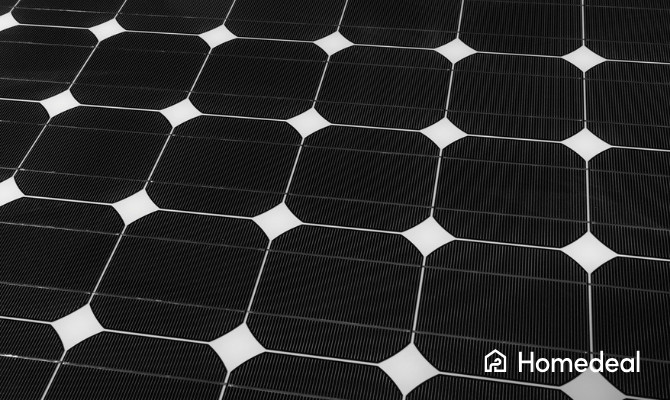 Detailopname van monokristallijne zonnepanelen met kenmerkende zwarte cellen en witte ruitvormige tussenruimtes.