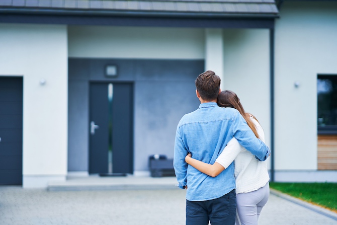 Koppel staat omarmend voor een huis