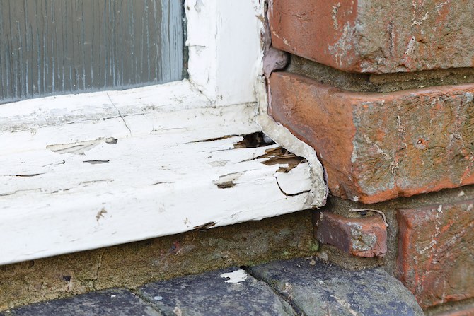 Close up foto van een rottend houten kozijn die gerepareerd moet worden