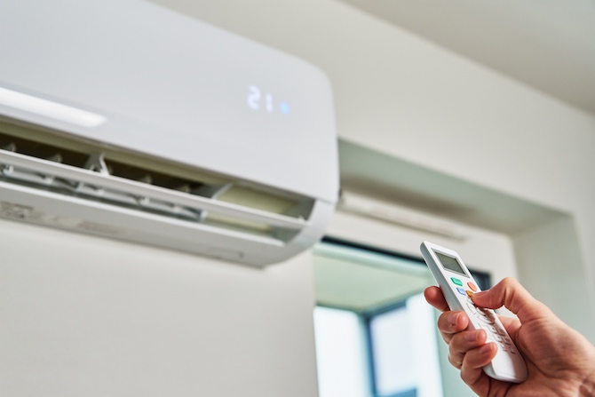 Gebruiker stelt met de afstandbediening de temperatuur van de airco in huis in.