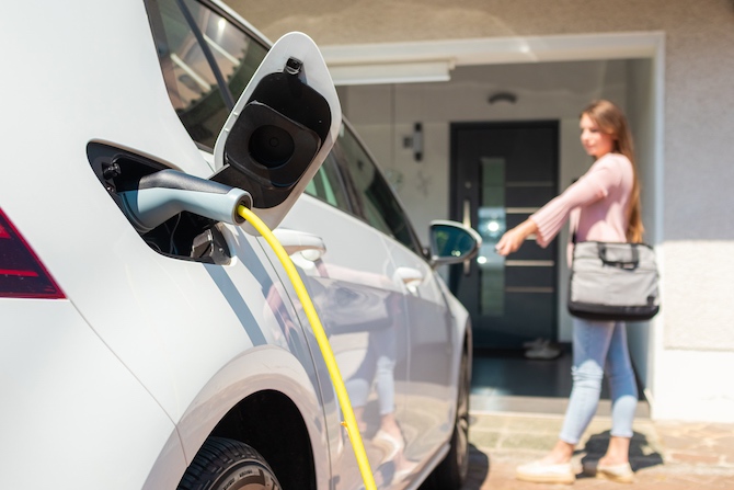 Vrouw laadt haar auto op met een laadpaal voor thuis