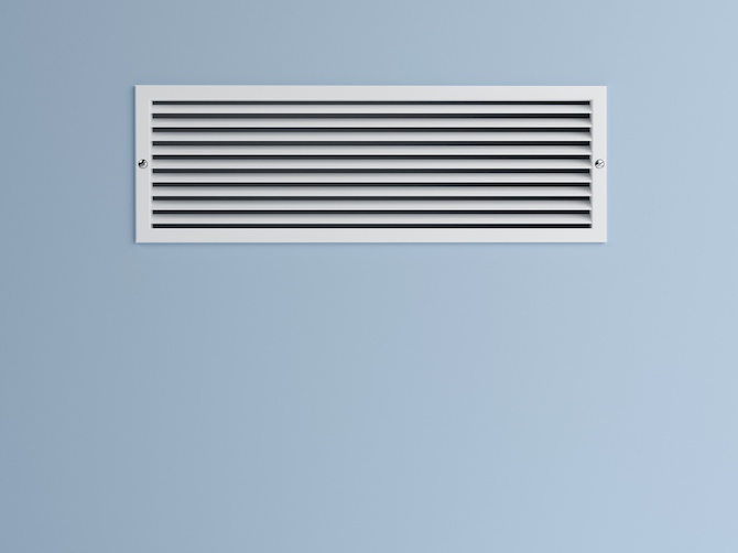 Wit ventilatierooster in een blauwe muur