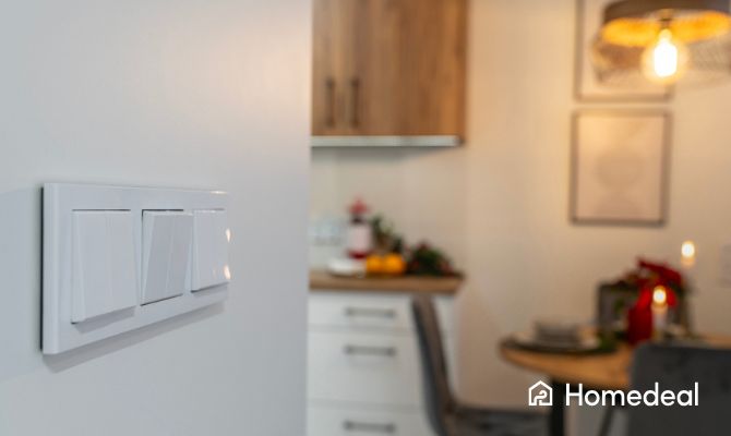 Close up van meerdere lichtschakelaars met op de achtergrond een keuken