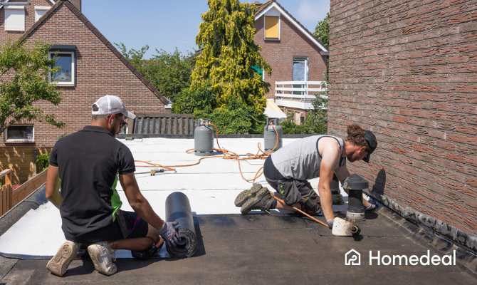 Twee mannen brengen een laag bitumen aan op een plat dak na isoleren
