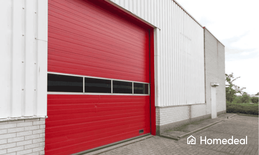 Bedrijfspand met grote rode roldeur, geschikt voor onder andere magazijn of werkplaats.