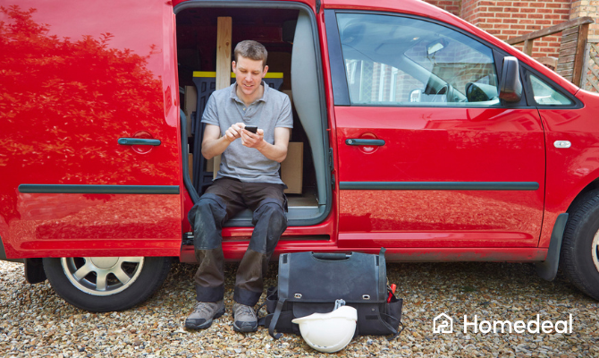 Vakman typt op mobiele telefoon terwijl hij in een busje zit