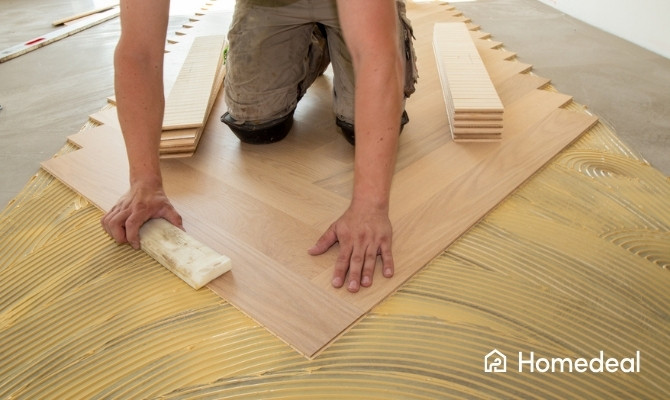 Vloerspecialist legt houten parketvloer in visgraatpatroon met lijm