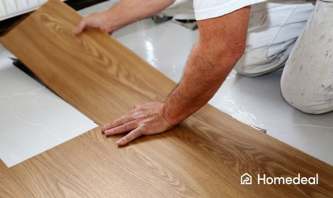 Vakman bezig met pvc vloer leggen door een houtlook plank in de lijm op de ondervloer te plaatsen.